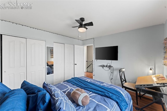 bedroom featuring ceiling fan, hardwood / wood-style floors, and two closets