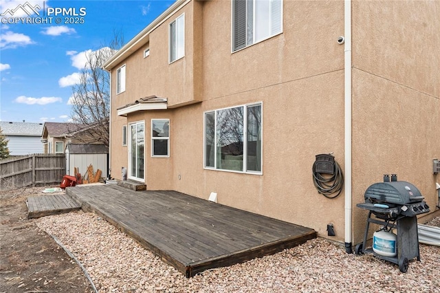 rear view of property featuring a storage unit and a deck