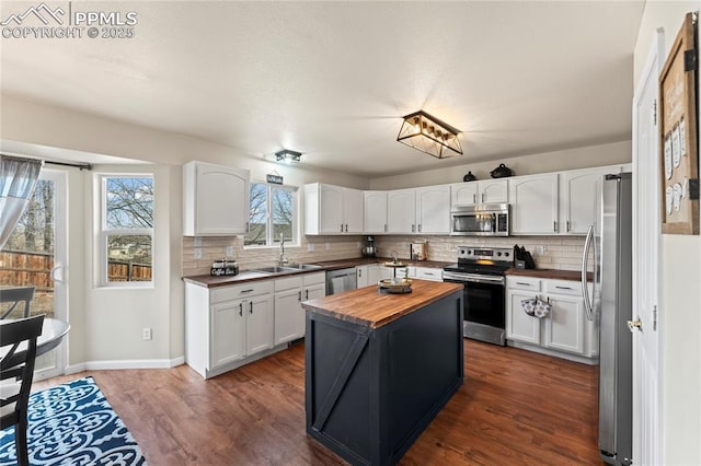 kitchen featuring butcher block counters, sink, white cabinetry, dark hardwood / wood-style floors, and stainless steel appliances