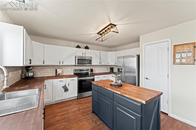 kitchen featuring appliances with stainless steel finishes, wood counters, blue cabinets, sink, and white cabinets