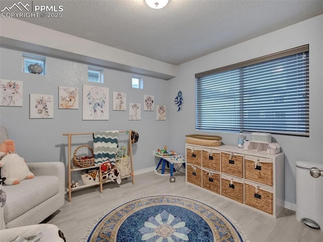 sitting room featuring plenty of natural light, light hardwood / wood-style floors, and a textured ceiling