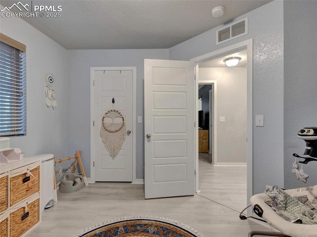 entryway with a textured ceiling and light wood-type flooring