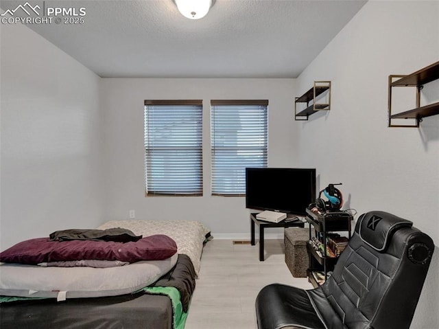 bedroom featuring light hardwood / wood-style flooring and a textured ceiling