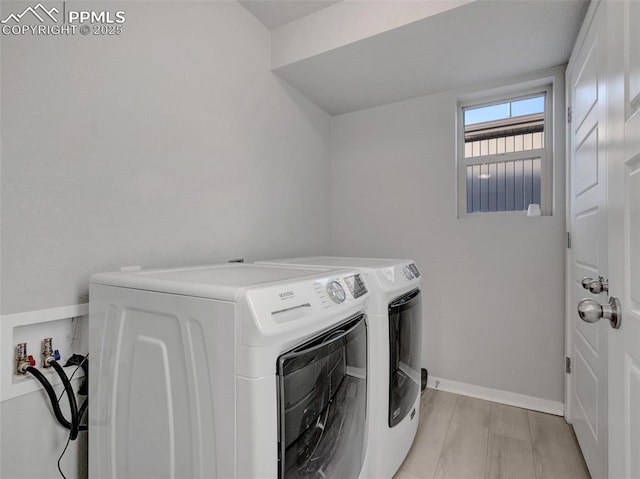 clothes washing area with light hardwood / wood-style floors and washing machine and clothes dryer