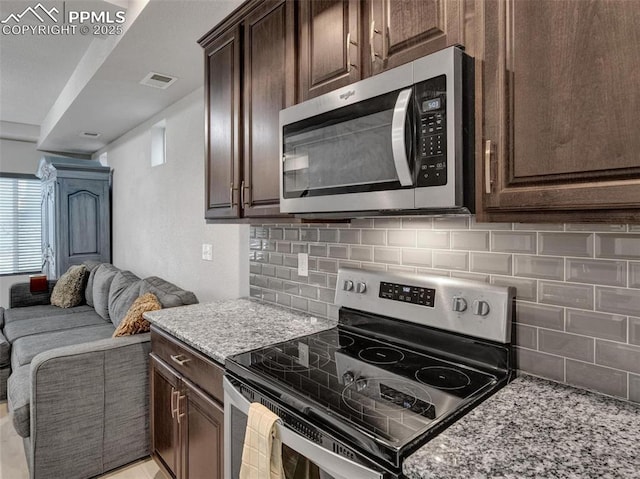 kitchen featuring light stone counters, dark brown cabinets, and appliances with stainless steel finishes