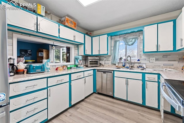 kitchen featuring white cabinetry, appliances with stainless steel finishes, sink, and a healthy amount of sunlight