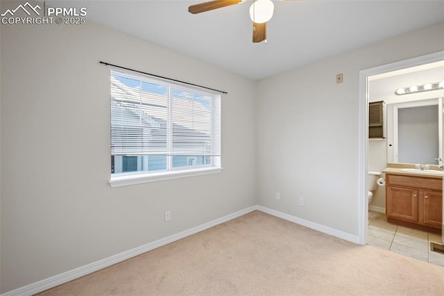 unfurnished bedroom with light carpet, sink, ceiling fan, and ensuite bathroom