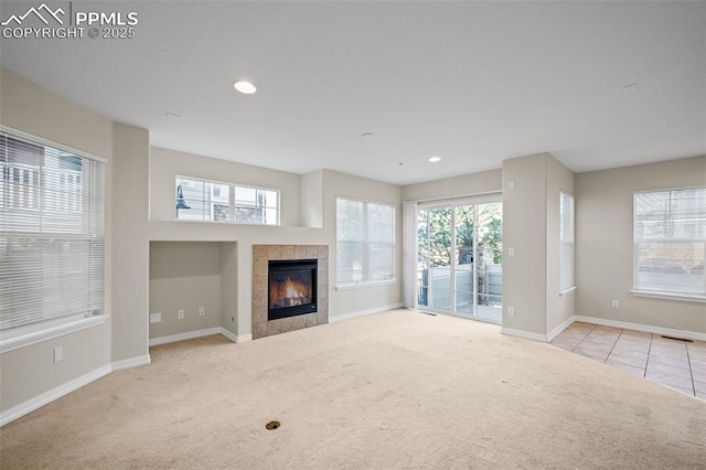 unfurnished living room featuring a tiled fireplace and light carpet