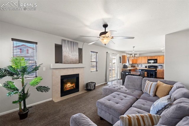 living room with ceiling fan with notable chandelier, a fireplace, and dark carpet