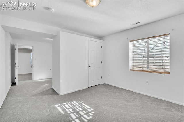 unfurnished room featuring light carpet and a textured ceiling