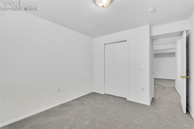 unfurnished bedroom with light colored carpet, a textured ceiling, and a closet