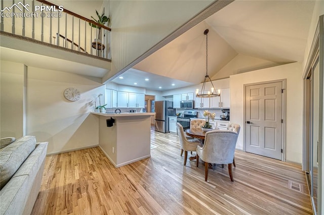 kitchen featuring a chandelier, light wood-type flooring, kitchen peninsula, stainless steel appliances, and white cabinets