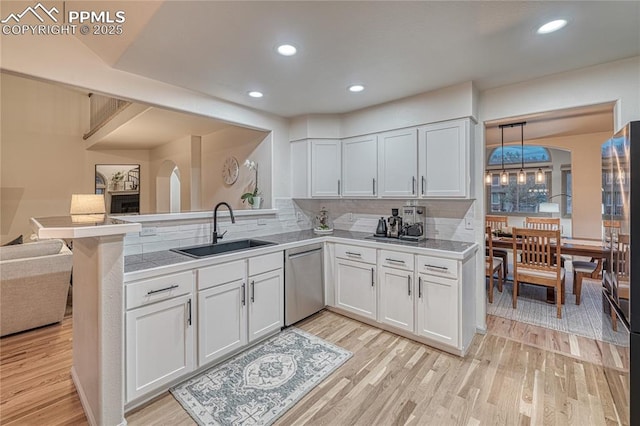 kitchen with stainless steel dishwasher, kitchen peninsula, sink, and white cabinets