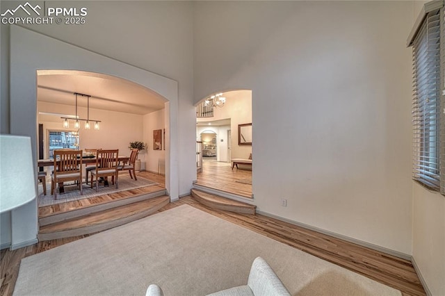 living room featuring a notable chandelier, wood-type flooring, and a high ceiling