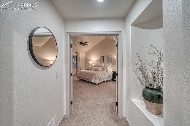 hall featuring vaulted ceiling and light carpet