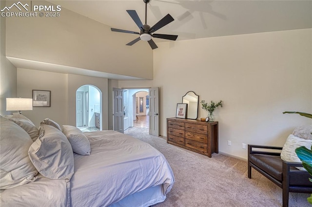 carpeted bedroom with ceiling fan, connected bathroom, and high vaulted ceiling