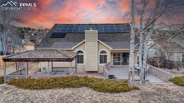 back house at dusk with a gazebo and solar panels