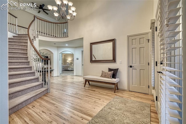 foyer entrance featuring a towering ceiling, an inviting chandelier, and light hardwood / wood-style flooring