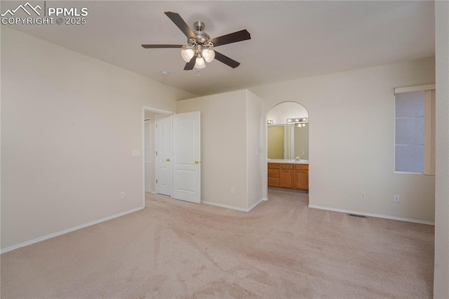 unfurnished bedroom with ceiling fan, light colored carpet, and ensuite bathroom