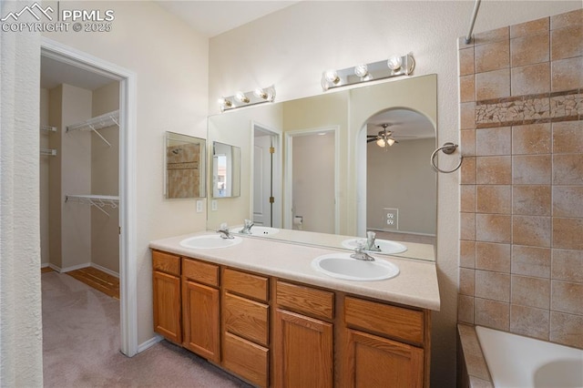 bathroom with ceiling fan, vanity, and a washtub