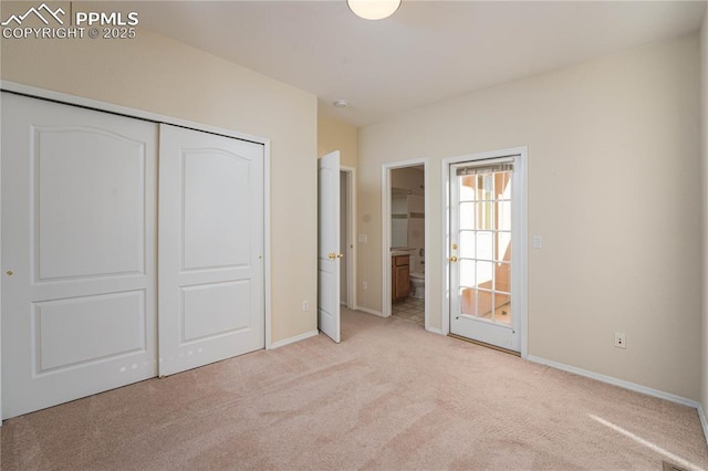 unfurnished bedroom featuring light colored carpet, ensuite bath, and a closet