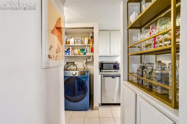 laundry room featuring laundry area, washer / clothes dryer, a textured ceiling, and light tile patterned floors