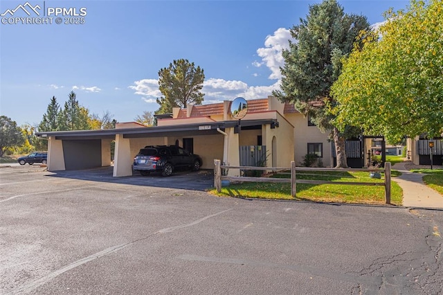 view of front of home with covered parking, fence, and stucco siding