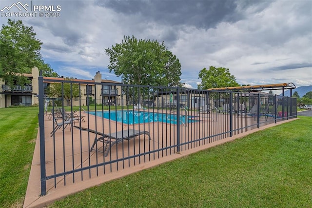 pool featuring a patio area, fence, and a lawn