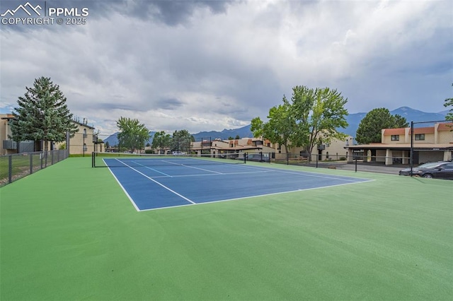 view of tennis court featuring fence and a mountain view