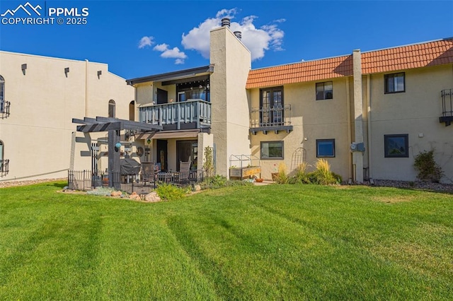 back of property featuring a lawn, a chimney, a tiled roof, a pergola, and stucco siding