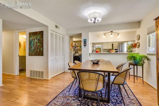 dining area with washer / dryer, light wood-type flooring, visible vents, and baseboards