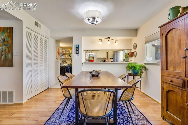 dining room featuring baseboards, light wood-style flooring, visible vents, and washer and dryer