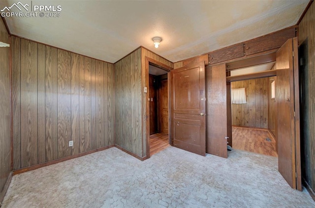 unfurnished bedroom with light colored carpet and wood walls