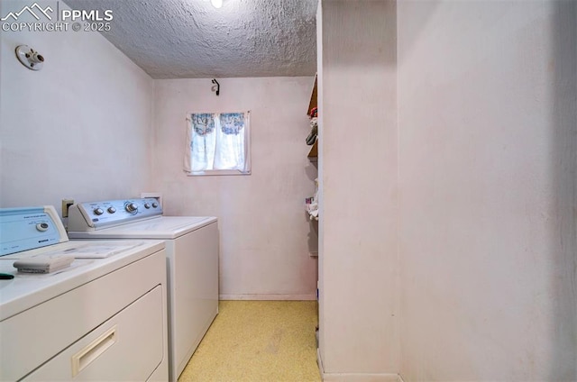 laundry area with independent washer and dryer and a textured ceiling