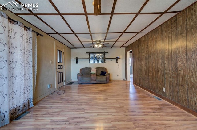 interior space featuring ceiling fan, coffered ceiling, light hardwood / wood-style flooring, and wood walls