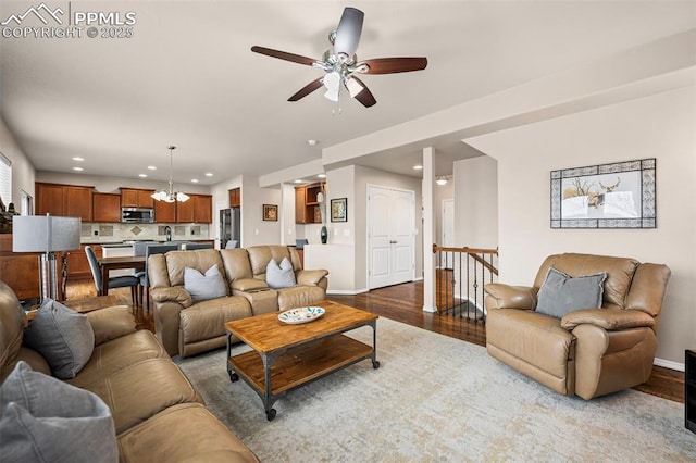 living area featuring baseboards, ceiling fan with notable chandelier, light wood-type flooring, and recessed lighting