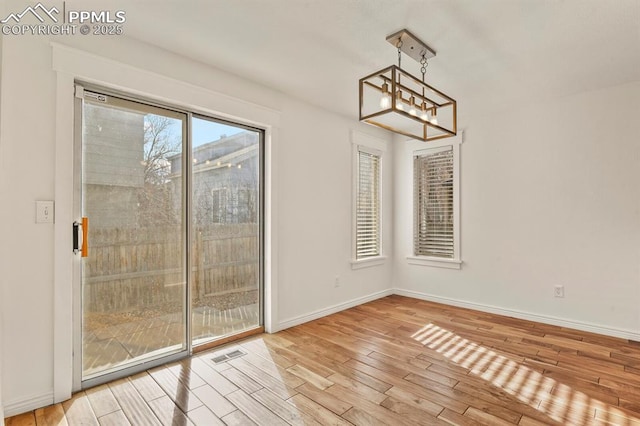 unfurnished dining area with a notable chandelier and light wood-type flooring