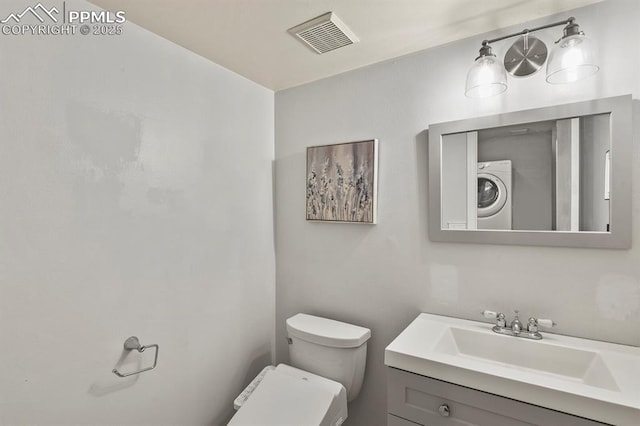 bathroom with vanity, stacked washer / drying machine, and toilet