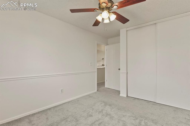 unfurnished bedroom with ceiling fan, light colored carpet, a closet, and a textured ceiling