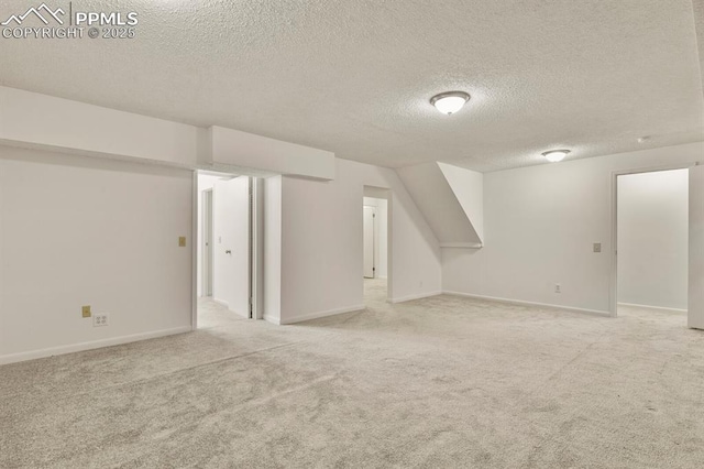 additional living space featuring light colored carpet and a textured ceiling