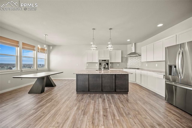 kitchen with white cabinets, wall chimney range hood, stainless steel fridge, and tasteful backsplash