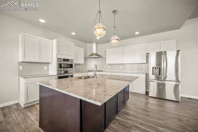 kitchen featuring dark wood-style floors, appliances with stainless steel finishes, white cabinetry, a sink, and wall chimney range hood