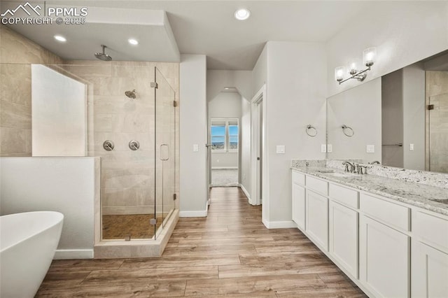 full bath with a stall shower, baseboards, a soaking tub, wood finished floors, and vanity