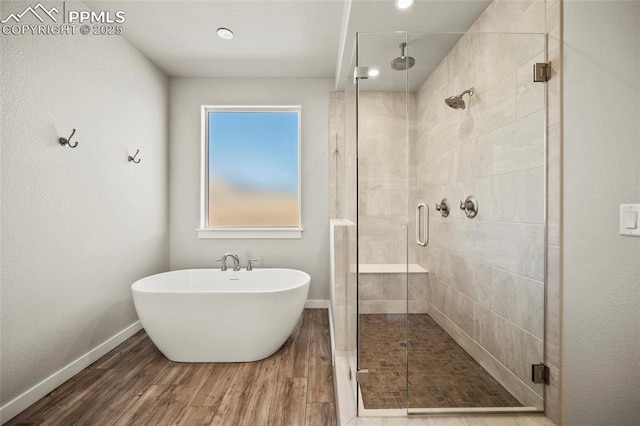 full bath with a soaking tub, a shower stall, baseboards, and wood finished floors