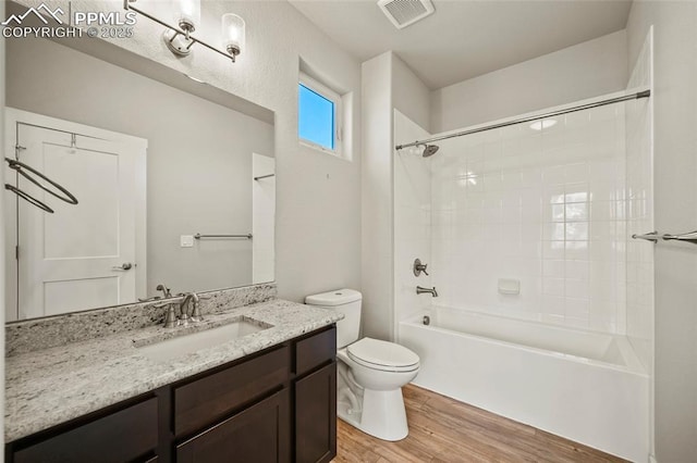 full bath with shower / bathtub combination, toilet, wood finished floors, vanity, and visible vents