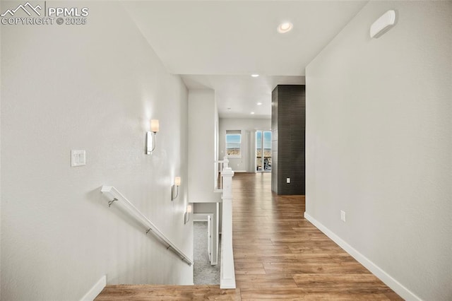 interior space featuring recessed lighting, baseboards, wood finished floors, and an upstairs landing