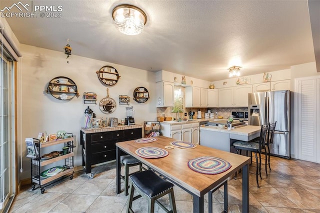 dining room featuring sink, light tile patterned floors, and a textured ceiling