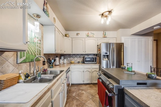 kitchen featuring sink, light tile patterned floors, stainless steel appliances, tasteful backsplash, and white cabinets