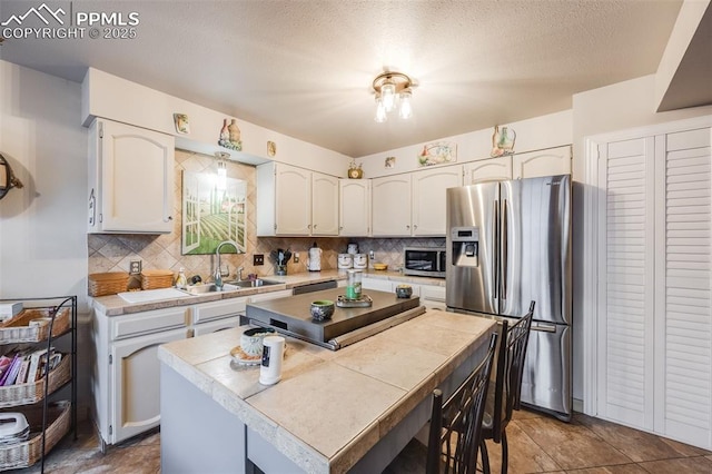 kitchen featuring sink, tasteful backsplash, a center island, appliances with stainless steel finishes, and white cabinets