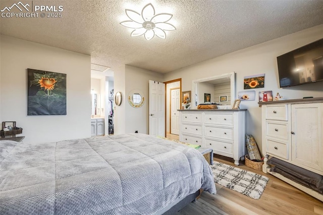 bedroom featuring wood-type flooring, a textured ceiling, and ensuite bathroom